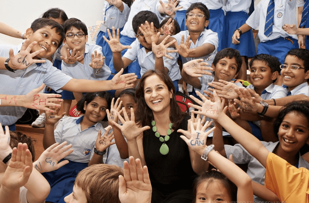 A teacher with smiling students holding up palms with 'I can' written on them