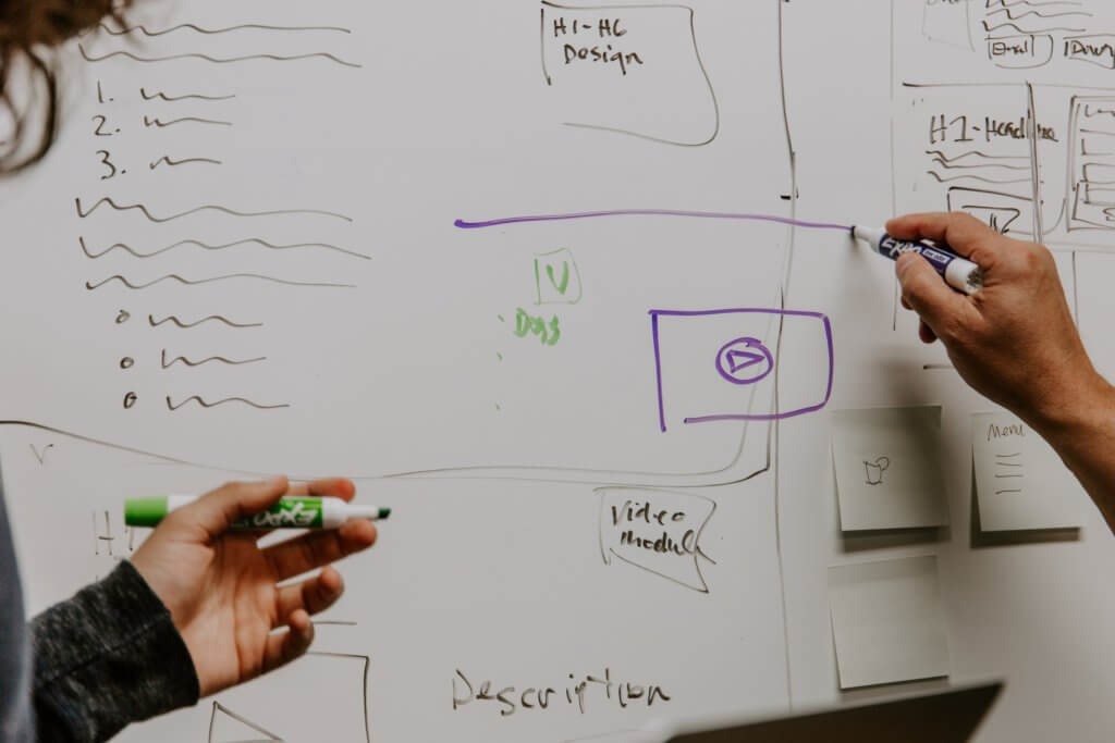 Hands sketching a plan on a whiteboard