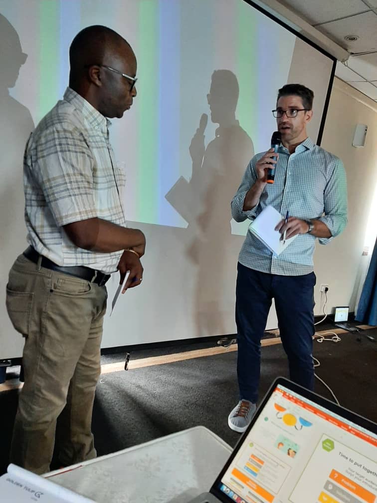 A participant presenting with a microphone during a design thinking session in Uganda